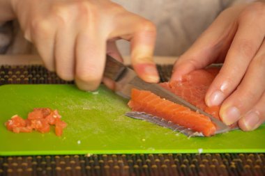 Kadın eli, mutfaktaki yeşil tahtada somonu salataya çevirdi.