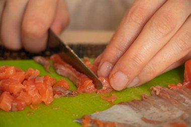 Kadın eli, mutfaktaki yeşil tahtada somonu salataya çevirdi.