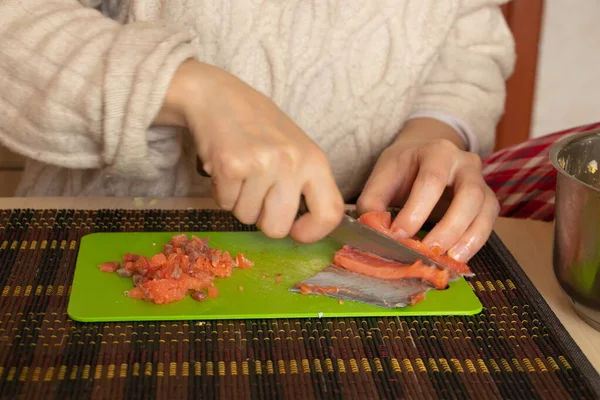 女性の手でサーモンをキッチンの緑の板の上のサラダに切り — ストック写真