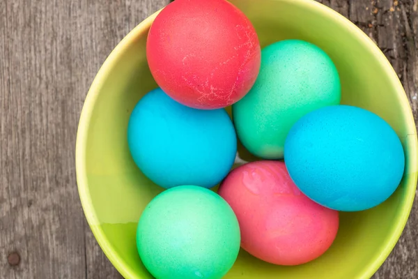 multi-colored easter eggs lie on an old wooden board, on quarantine on Easter