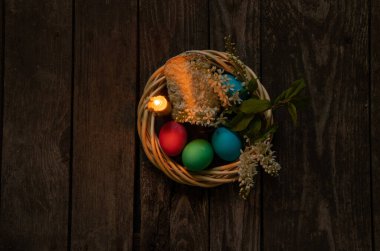 Paskalya yemeği, renkli tavuk yumurtası ve mum alevi eski ahşap bir masada akşam yemeği.