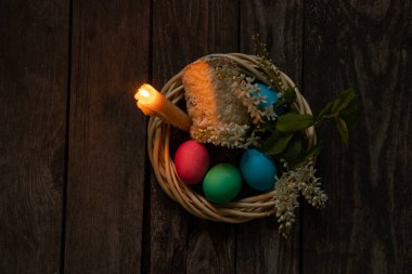 Paskalya yemeği, renkli tavuk yumurtası ve mum alevi eski ahşap bir masada akşam yemeği.