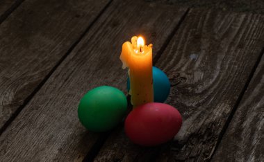 Paskalya yemeği, renkli tavuk yumurtası ve mum alevi eski ahşap bir masada akşam yemeği.