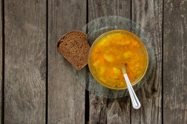Bezelye çorbası ve tahtadan bir masada bir dilim kahverengi ekmek.