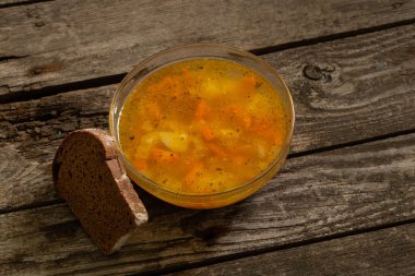 Bezelye çorbası ve tahtadan bir masada bir dilim kahverengi ekmek.