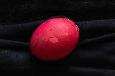 Tıbbi maske siyah ve üstünde Paskalya boyunca kırmızı bir Paskalya yumurtası yatıyor.