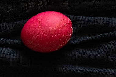 Tıbbi maske siyah ve üstünde Paskalya boyunca kırmızı bir Paskalya yumurtası yatıyor.