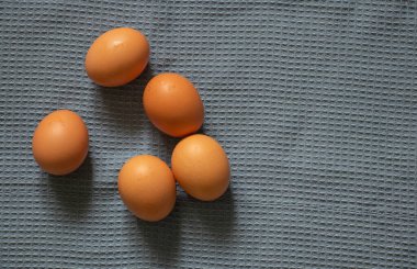 Tabaktaki sarı tavuk yumurtaları masa örtüsünün üzerinde yatıyor.