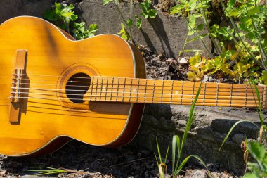Ahşap kahverengi gitar Ukrayna 'nın bahar çimenlerinde, sokakta taş bir yolda yatıyor.