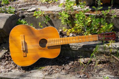 Ahşap kahverengi gitar Ukrayna 'nın bahar çimenlerinde, sokakta taş bir yolda yatıyor.
