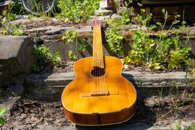 Ahşap kahverengi gitar Ukrayna 'nın bahar çimenlerinde, sokakta taş bir yolda yatıyor.