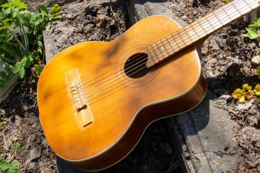Ahşap kahverengi gitar Ukrayna 'nın bahar çimenlerinde, sokakta taş bir yolda yatıyor.