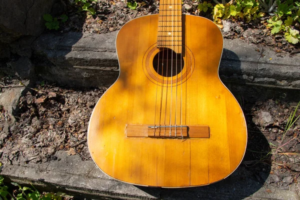 木製の茶色のギターはウクライナの春の草の通りの石の道にあります — ストック写真