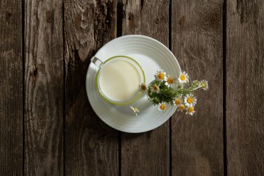 Sabahları masada bir bardak süt ve papatya.