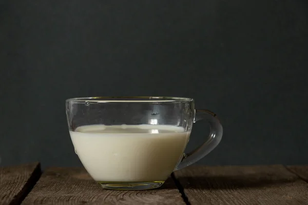 在黑暗中厨房的一张木制桌子上喝着一杯牛奶 — 图库照片