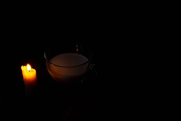 部屋の木のテーブルの上にミルクとロウソクの炎とカップ — ストック写真