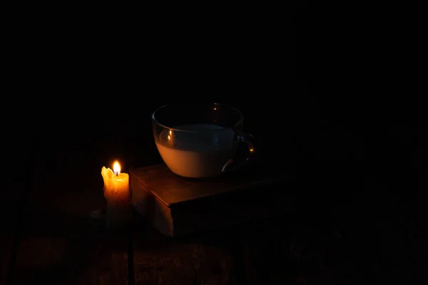 Kerzenflamme Und Tasse Mit Milch Und Einem Buch Auf Einem — Stockfoto