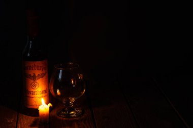 Ukrayna, Dnipro - Nisan 06, 2020. Bodrumda bulunan üçüncü Reich 'ın Horneburger 1939 viskisi evin karanlık bir odasında mumların yanında duruyor.