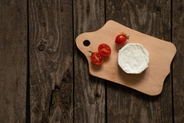 Yumuşak brie peyniri ve kiraz domatesleri masada.