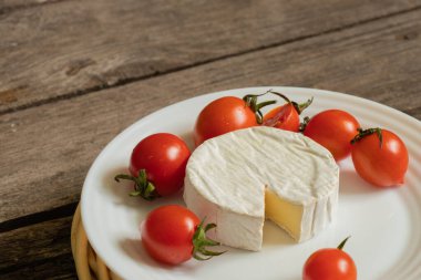 Yumuşak brie peyniri ve kiraz domatesleri masada.