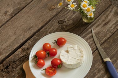 Yumuşak brie peyniri ve kiraz domatesleri masada.