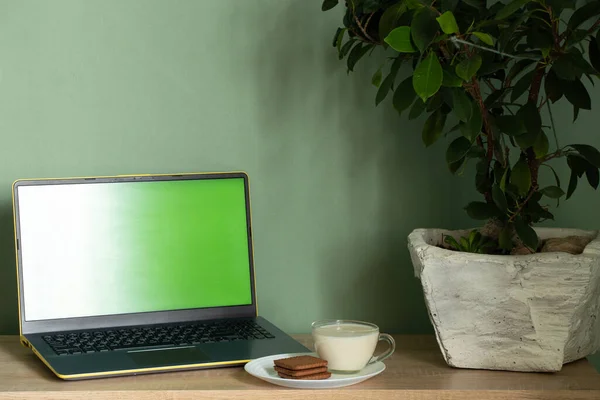 laptop with green screen yogurt with cookies on a table in a room at home