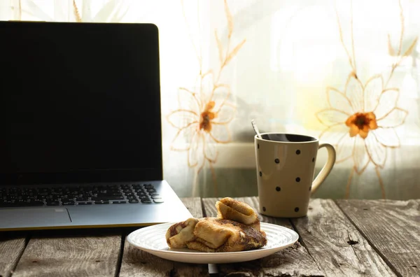 盘子里的凝块煎饼 木制桌子上的一杯茶和笔记本电脑 — 图库照片