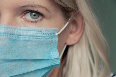 2020 'deki karantina salgını sırasında yüzünde tıbbi maske olan genç bir Ukraynalı kadının resmi.