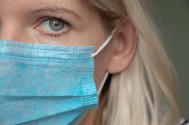 2020 'deki karantina salgını sırasında yüzünde tıbbi maske olan genç bir Ukraynalı kadının resmi.