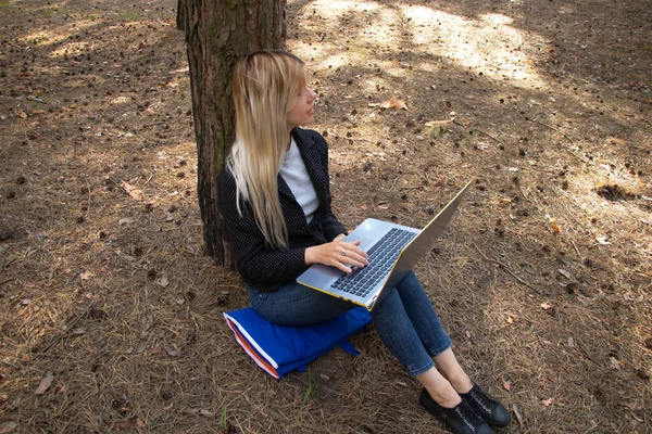 Ukraynalı kız, karantina altındaki kozalaklı bir ormanda dizüstü bilgisayarla oturuyor.