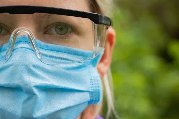 girl in a medical mask and glasses on the street close-up during a pandemic