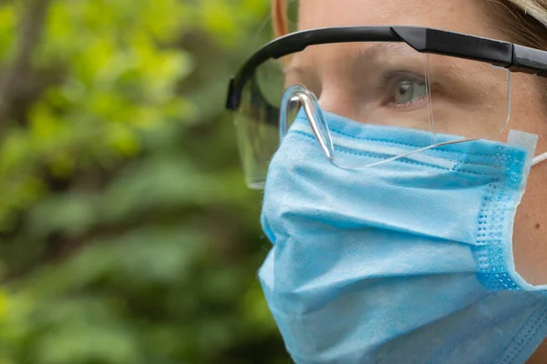 girl in a medical mask and glasses on the street close-up during a pandemic