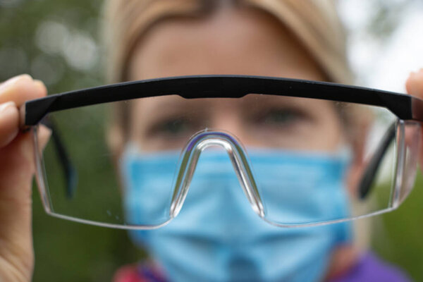 girl in a medical mask and glasses on the street close-up during a pandemic