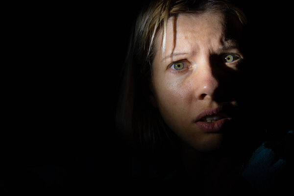 женское лицо в темноте, освещенное фонарем
