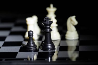 Bir fenerle aydınlatılmış karanlık bir odada satranç tahtasında satranç taşları.