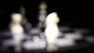 Bir fenerle aydınlatılmış karanlık bir odada satranç tahtasında satranç taşları.