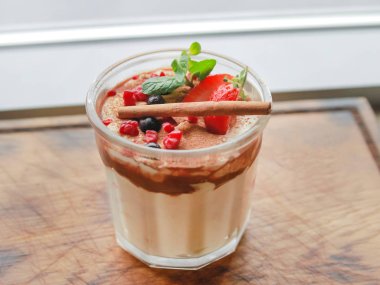 Bardakta tatlı, tarçın çubuğuyla süslenmiş, böğürtlen ve nane yaprağı dilimleri.