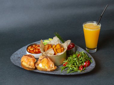 İtalyan kahvaltısı - kızarmış patates, fasulye, yumuşak peynir ve somonlu sandviç ve roka ve soslu domates salatası.