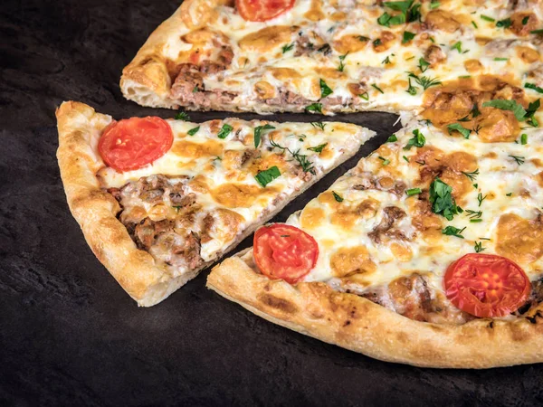 Pizza with meat, tomatoes, and cheese. A slice of pizza lies next to a whole pizza