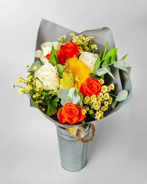 A bouquet of flowers is in a bucket of galvanized iron on a light background — Stock Photo, Image