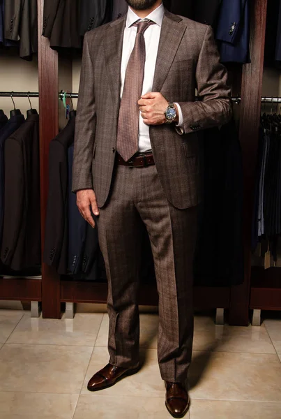 A young man in a classic suit stands in the trading floor of a men's clothing store, without a face — 图库照片