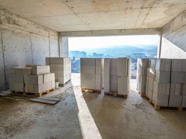 İnşaat halindeki çok katlı bir binanın odasındaki havalandırmalı beton bloklardan oluşan birkaç paket.