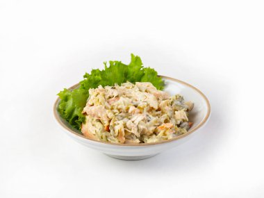 Jambonlu salata, tatlı biber, turşu, mayonez ile tatlandırılmış, marulla süslenmiş, beyaz bir tabakta.