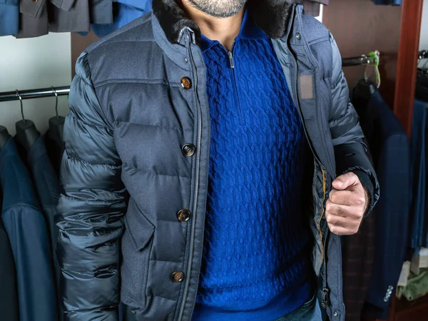 Um homem de camisola azul e jeans mostra um casaco curto — Fotografia de Stock