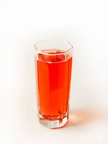 Vidrio facetado con una bebida de color rojo sobre un fondo blanco, diseño vertical — Foto de Stock