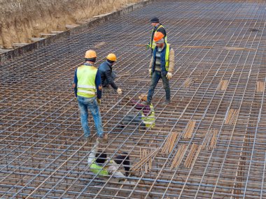 Birkaç işçi, yüksek bir binanın temelini atmak için takviye bir çerçeve hazırlıyorlar. Editör Fotoğrafı