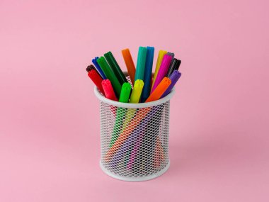 Pembe arka planda renkli kalemler bulunan aksesuarları yazmak için kullanılan beyaz cam kaplama. Yan görünüm, kapat