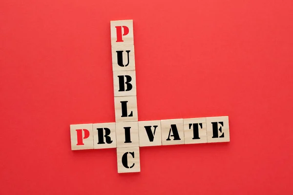 Kırmızı arka planda tahta bloklarda özel ve kamusal kavram bulmacaları. Bulmaca ipuçlarını kavra