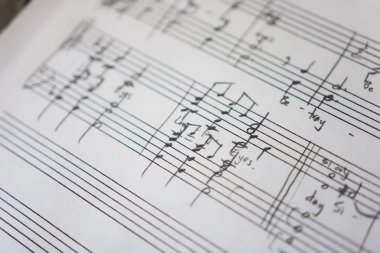 Temiz beyaz kağıda elle yazılmış notalar.