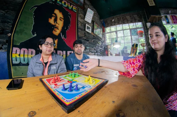 Fisheye tiro de hombres y mujeres jóvenes jugando ludo juego de mesa en un café —  Fotos de Stock